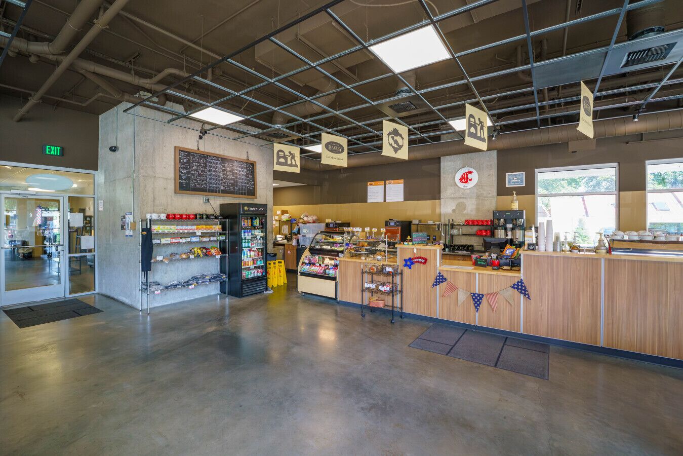 Eine Bäckereitheke mit einer Speisekarte, einer Kühltruhe und einer Kaffeestation.