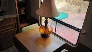 A wooden desk with a lamp, a chair, and a window with a view of the outside.