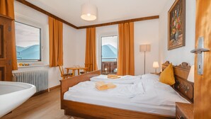 A hotel room with a wooden bed, a view of mountains, a balcony, and a bathroom. - Panoramaperle by Interhome (Neukirchen am Großvenediger)