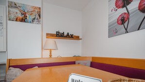 A room with a wooden table, a 'welcome' sign, a lamp, a shelf with 'RELAX' sign, and artwork on the walls. - Panoramaperle by Interhome (Neukirchen am Großvenediger)