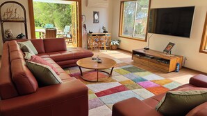 En stue med en hjørnesofa, et sofabord, et fladskærms-tv og et spiseområde med et bord og stole.