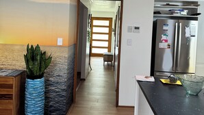 Et moderne køkken med et rustfrit stål køleskab, et træspisebord og en blå vase med grønne planter.