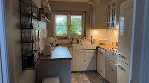 A compact kitchen with white cabinets, a built-in oven, and a window with blinds.