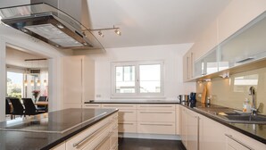 Une cuisine moderne avec un plan de travail noir, des armoires de couleur beige et une fenêtre qui laisse entrer la lumière naturelle.