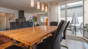 Un espace de salle à manger moderne avec une table en bois, des chaises noires et des luminaires suspendus.
