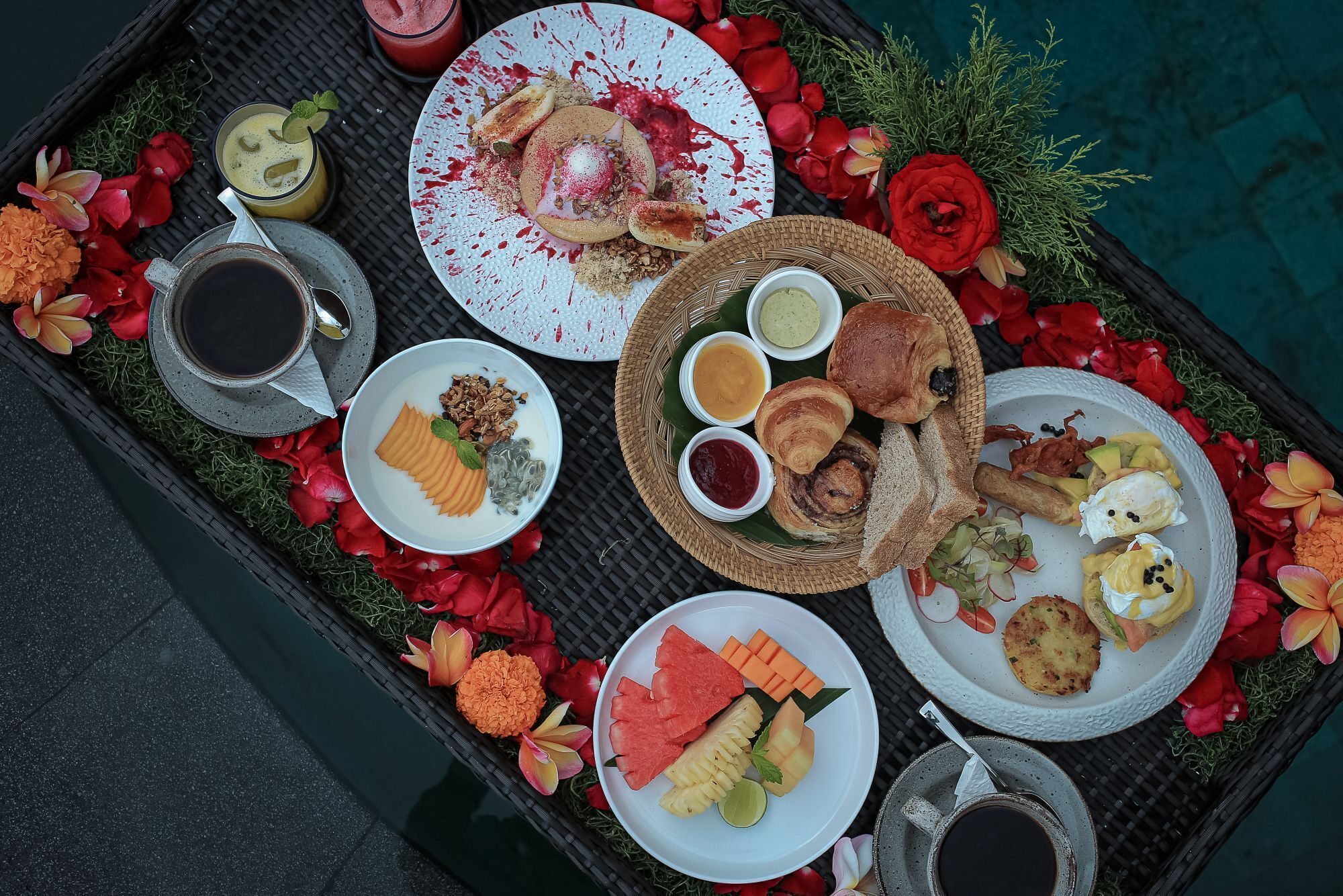 A tray with various food items, drinks, and decorative flowers.