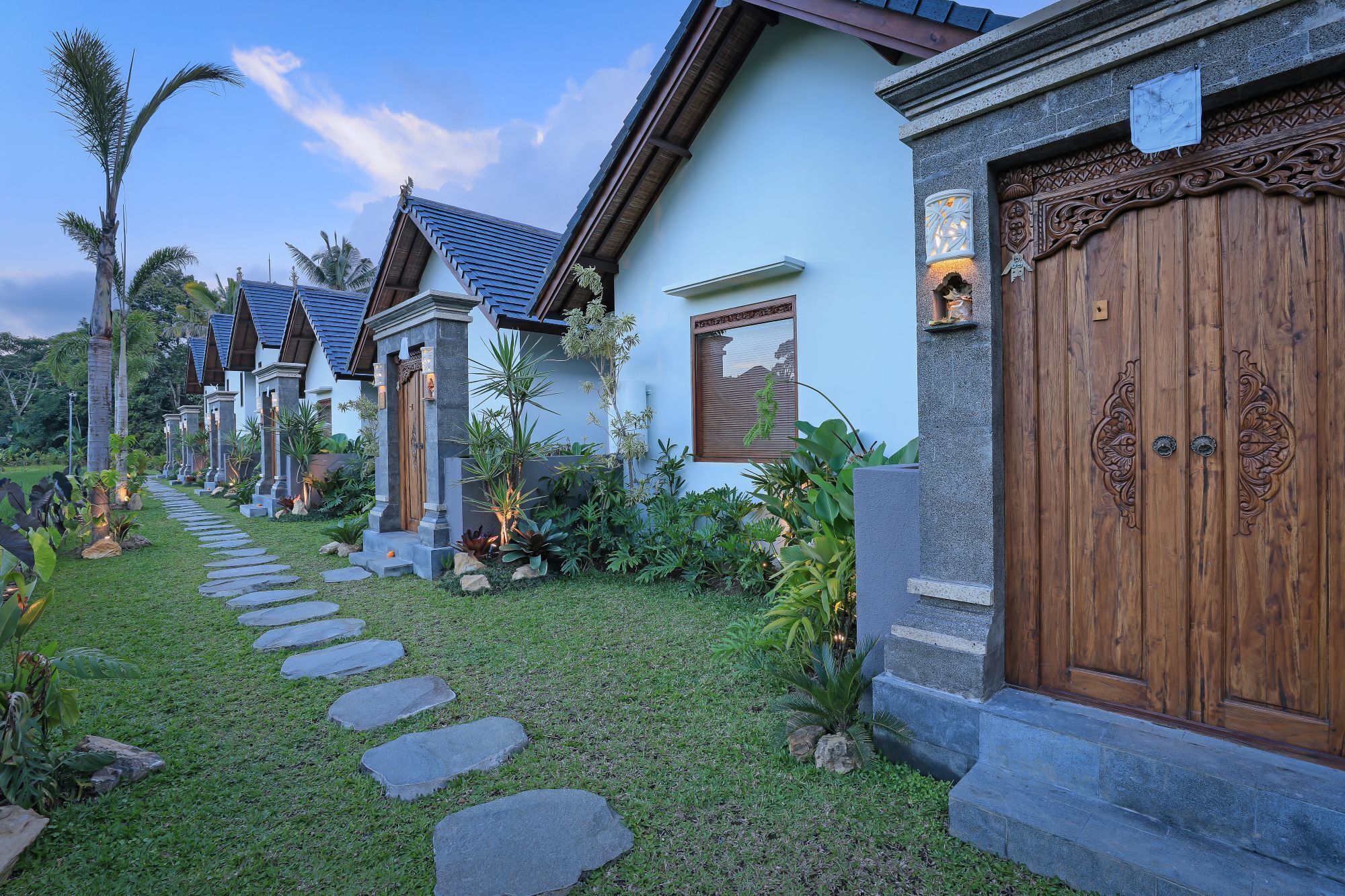 A pathway leading to a row of traditional-style buildings with wooden doors and stone steps.