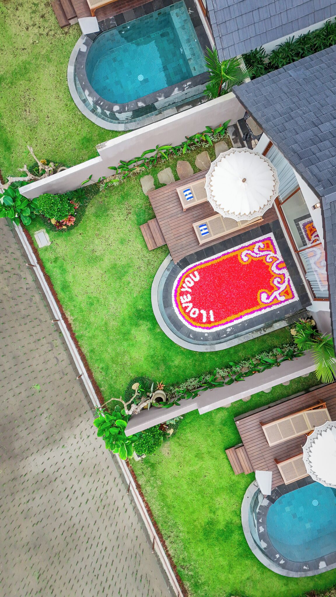 An aerial view of a residential property with a swimming pool, a patio area with seating, and a decorative flower bed with the text "WELCOME 2011".
