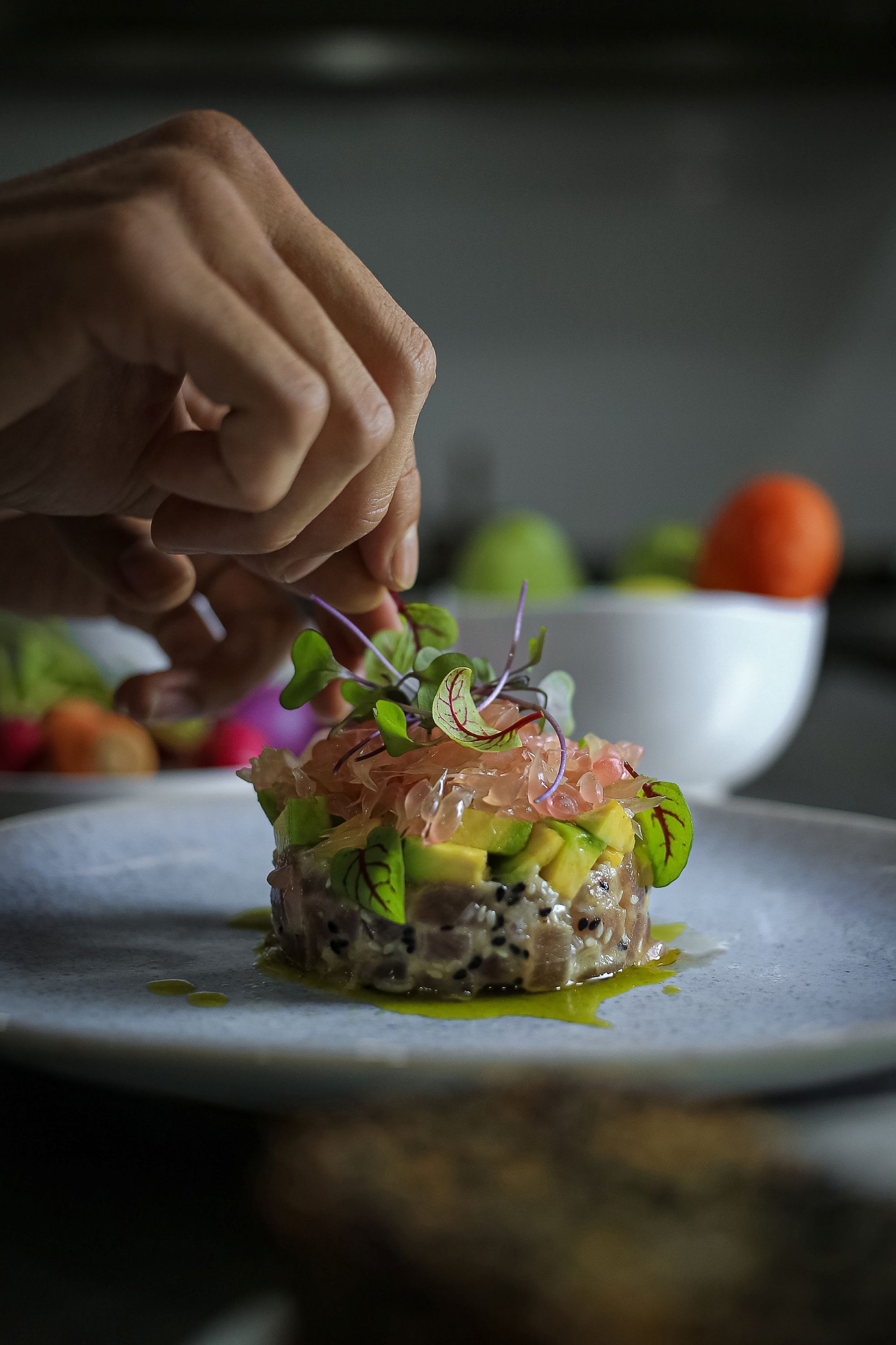 A close-up of a hand placing a garnish on a dish.
