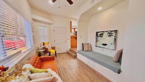 A modern living room with a wooden floor, a sofa, a bench, and a painting on the wall.