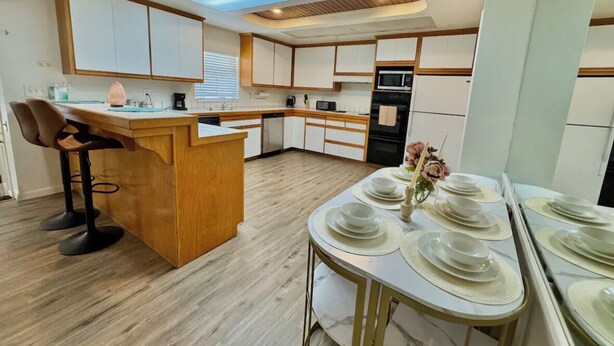 A modern kitchen with a central island, wooden bar stools, and a dining area set for six.