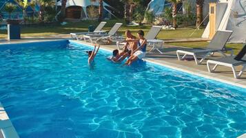 A swimming pool with lounge chairs and palm trees.