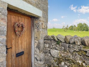 A rustic stone wall with a wooden door adorned with a heart-shaped wreath. - 2 bedroom accommodation in Skipton (Skipton)