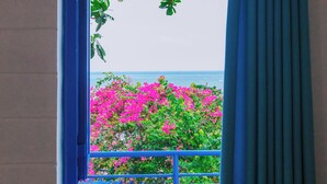A window with a view of pink flowers and a blue railing. - Irini Homestay & Hotel Mui Ne (Mui Ne)