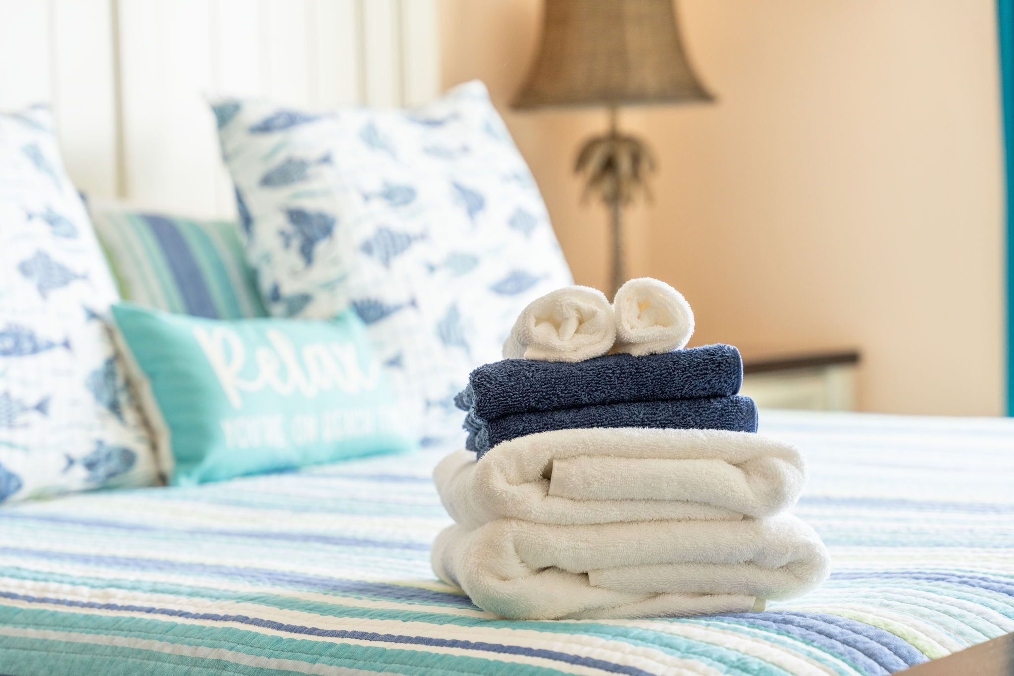 Una cama bien hecha con ropa de cama a rayas, una lámpara y almohadas decorativas.