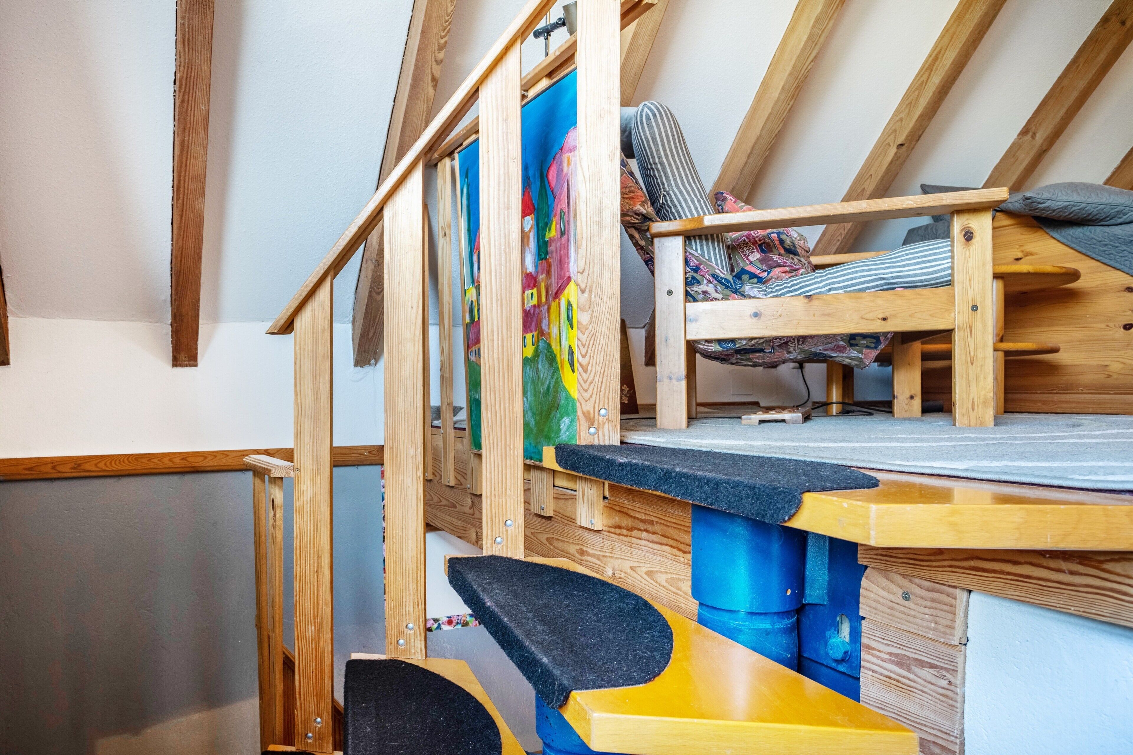 Une chambre de style loft avec un lit superposé, un bureau et un tableau coloré.