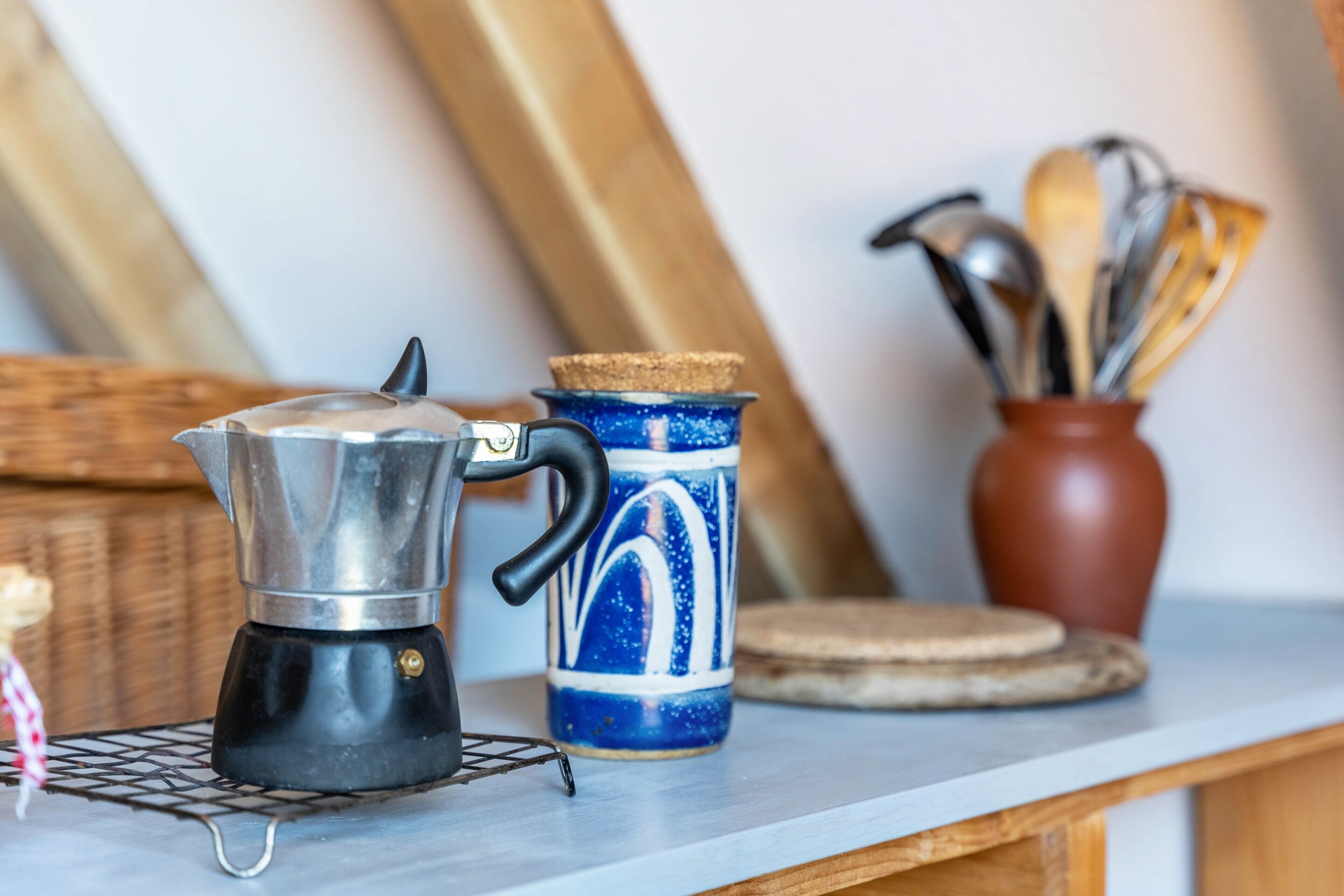 A kitchen counter with a coffee maker, a mug, and a utensil holder.