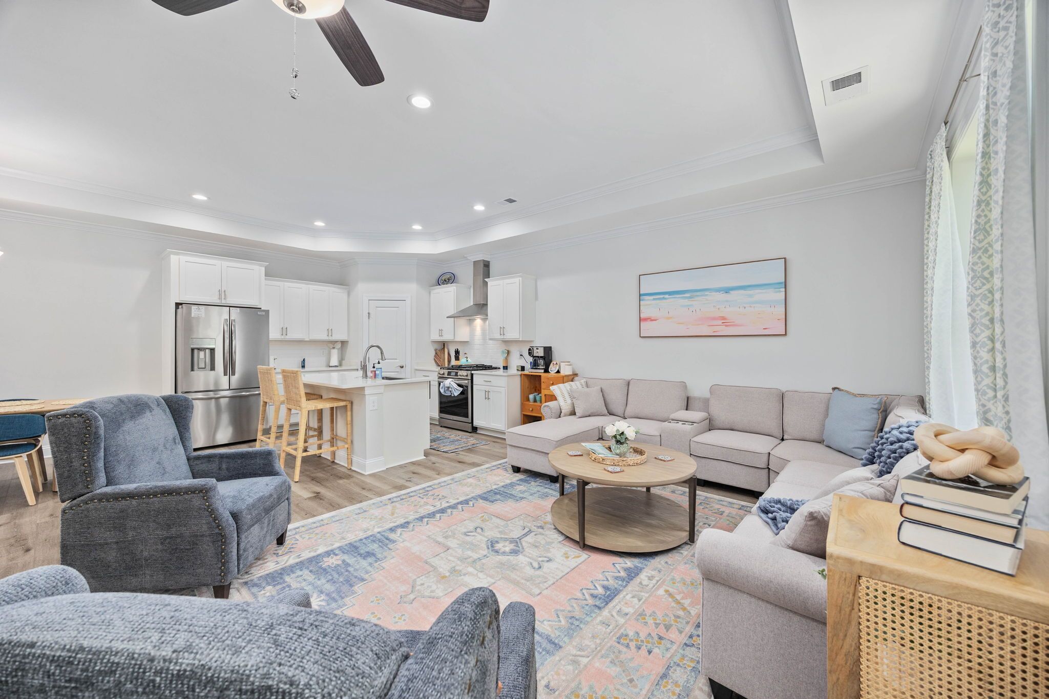 A modern living room with a sofa, armchair, coffee table, and a dining area with a table and chairs.