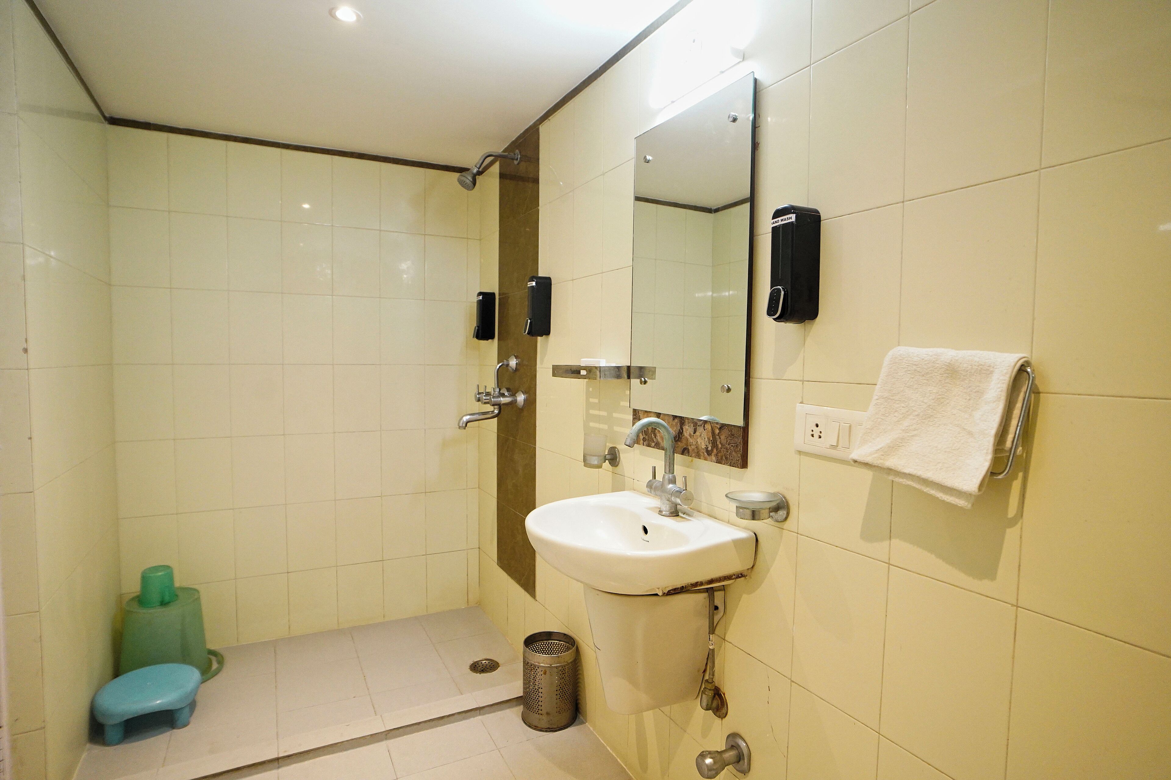 A bathroom with a sink, mirror, towel rack, and a green stool.