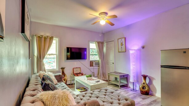 Ein Wohnzimmer mit einer Couch, einem Couchtisch, einem Fernseher und einem Deckenventilator.