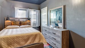 Ein Schlafzimmer mit Bett, Kommode und einem großen Spiegel.