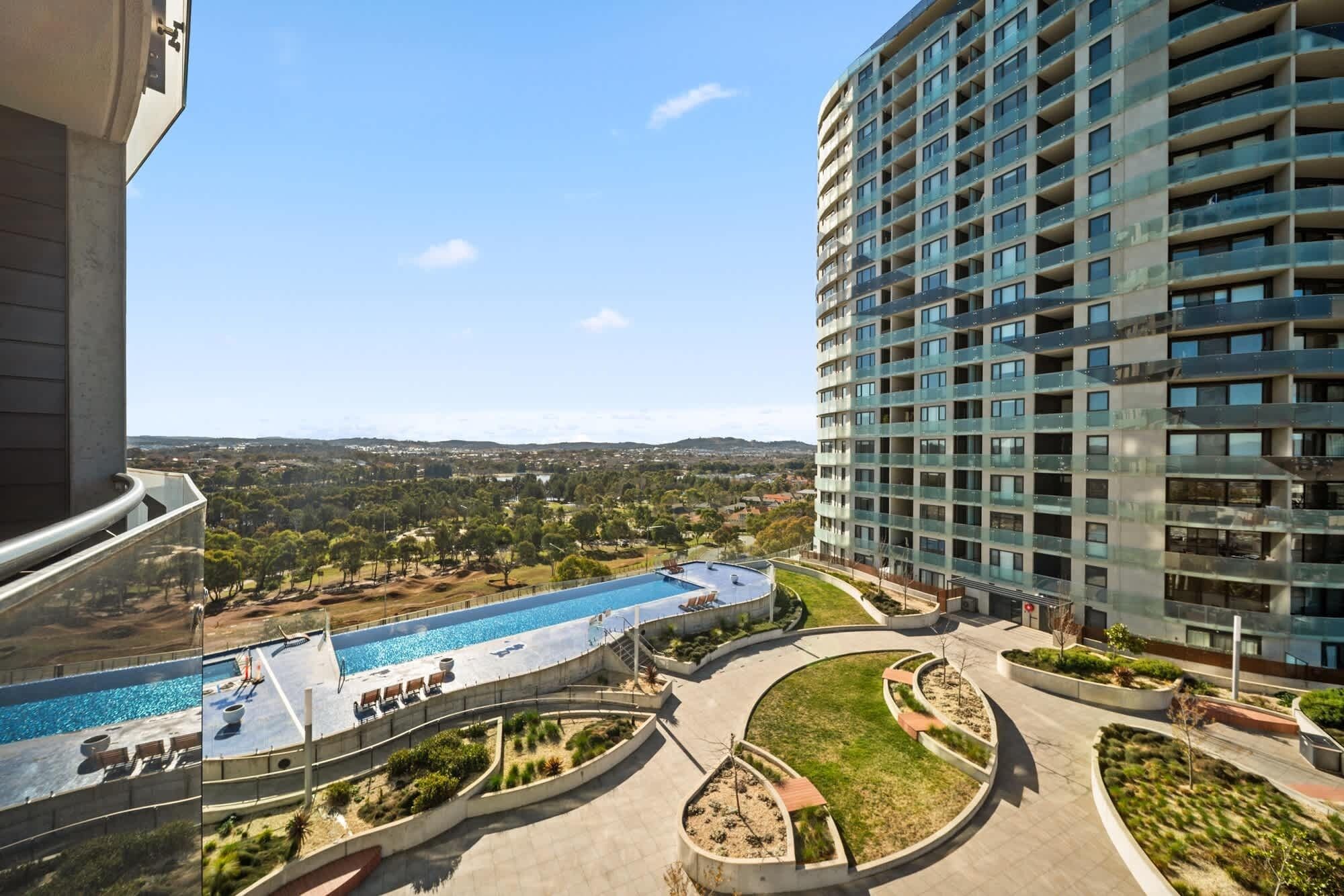 A high-rise building with a rooftop pool and landscaped areas.