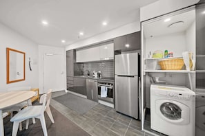 Une cuisine compacte équipée d’un réfrigérateur, d’un four et d’un lave-linge.