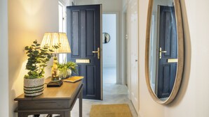 Un couloir avec une table en bois, une lampe et un miroir au mur.