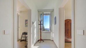 A hallway with a coat rack, a window with a view, and a wooden wardrobe. - Appartamento Vista Angera (Taino)