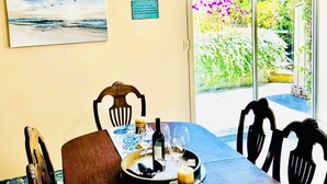 Ein Essbereich mit einem Tisch für zwei Personen, Blick auf den Garten durch eine Glastür und einem Bild an der Wand.