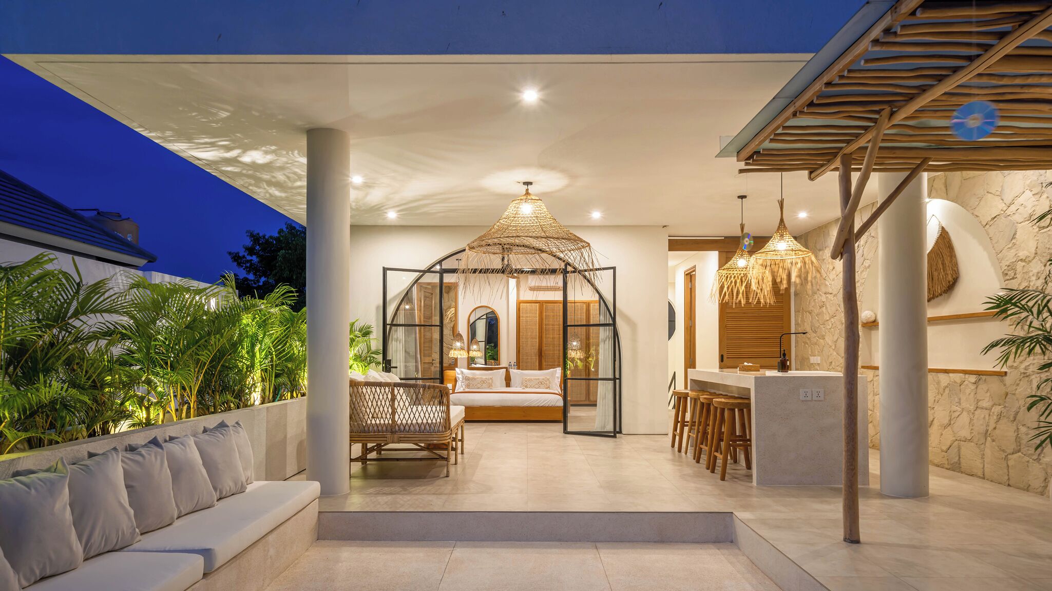 A modern outdoor living area with a covered seating area, a dining space, and a bedroom with a glass enclosure.