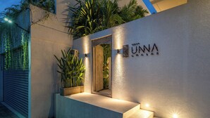 A modern building entrance with a concrete ramp leading up to a door, a potted plant, and a sign with the name "UNNA". - Villa Unna by Elite Havens (Kerobokan)