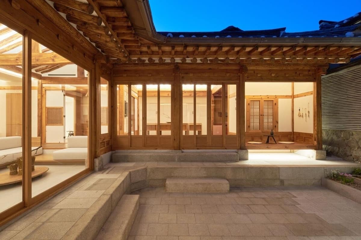 Un interior japonés tradicional con suelo de esteras de tatami, puertas correderas de madera y una pared de piedra.