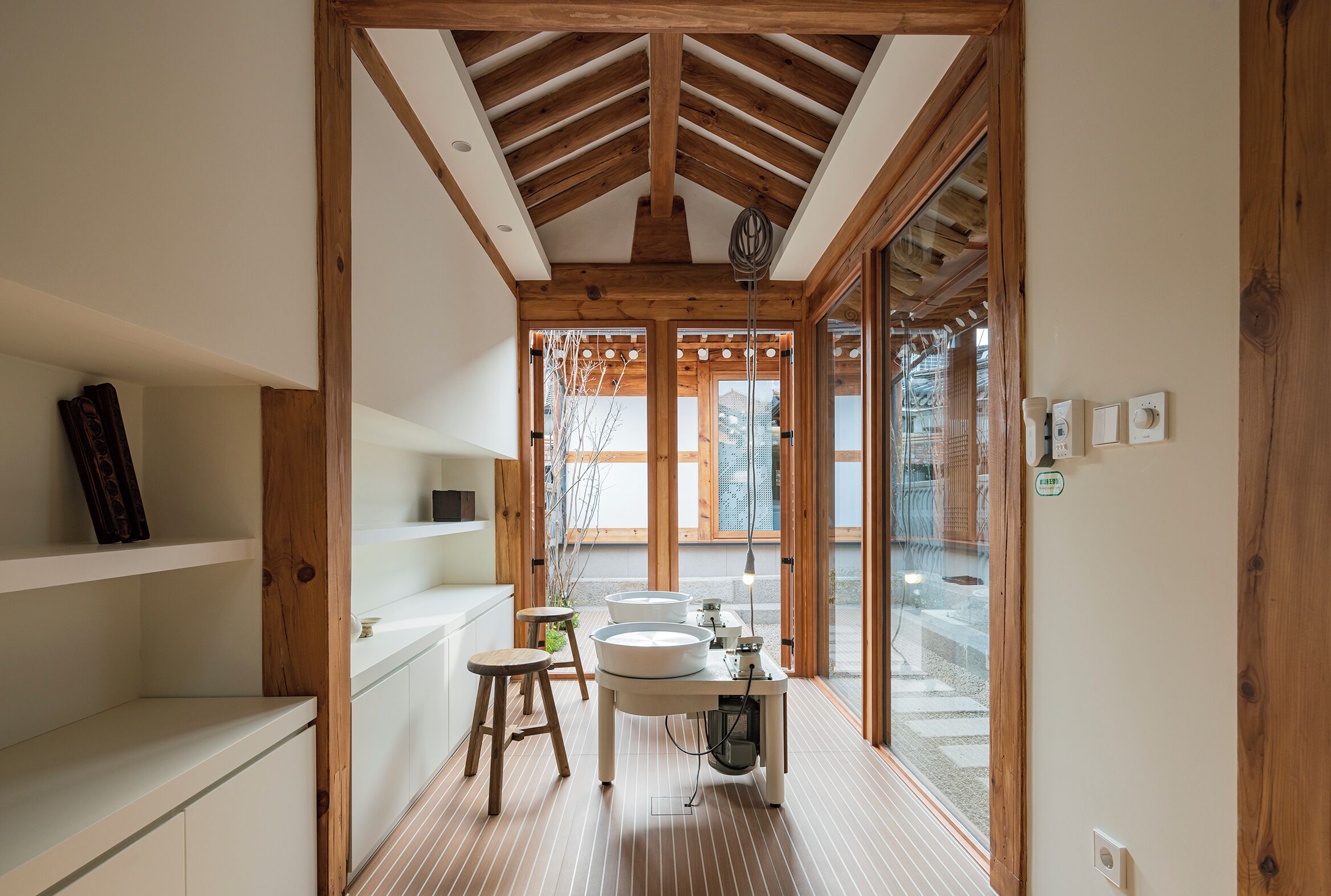 A modern bathroom with wooden beams, a sink, and a stool.