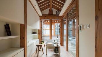 A modern bathroom with wooden beams, a sink, and a stool.
