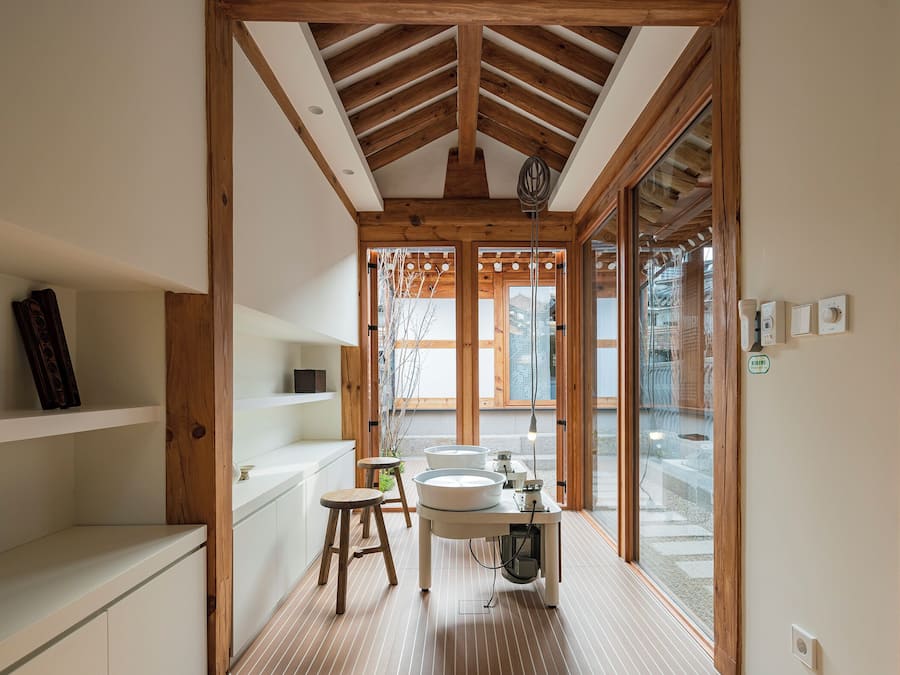 A modern bathroom with wooden beams, a sink, and a stool.