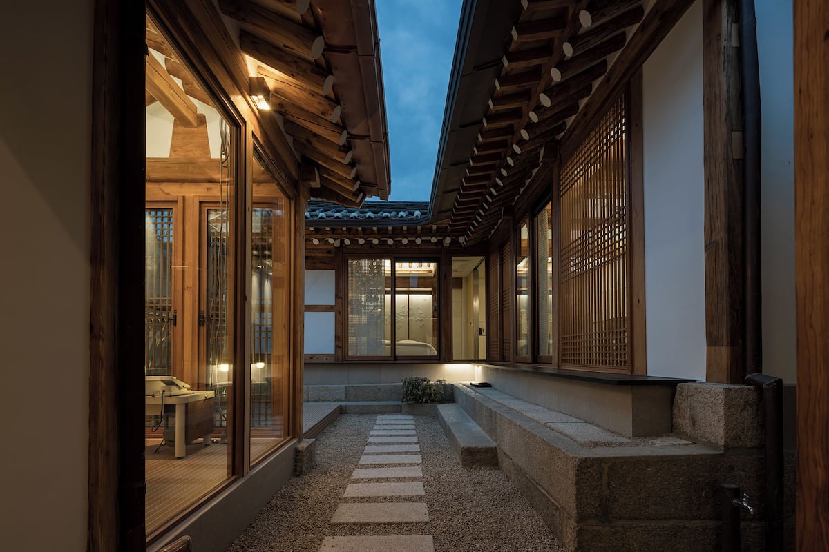 Un patio tradicional japonés con vigas de madera, suelo de tatami y puertas correderas.