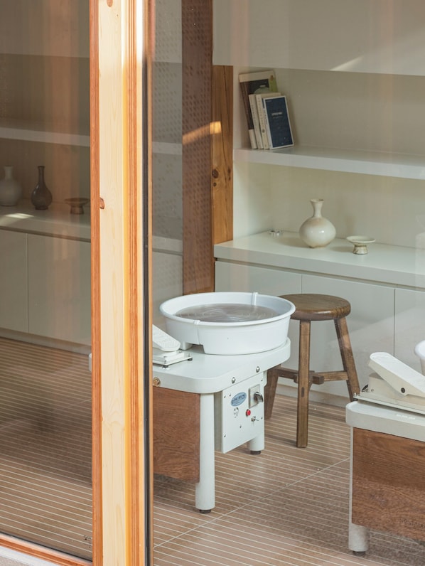 A bathroom with a bathtub, a wooden stool, and a shelf with books and vases. - Nostalgia Hanok Hotel (Seoul)