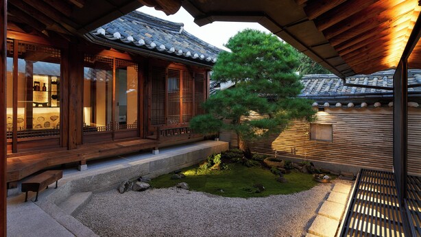 A traditional Japanese building with wooden architecture, a stone pathway, and a well-maintained garden with a pine tree. - Nostalgia Hanok Hotel (Seoul)