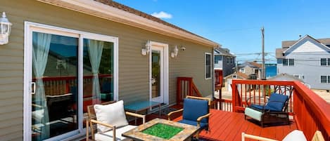 A covered outdoor area with a fire pit, seating, and a view of the surrounding neighborhood.