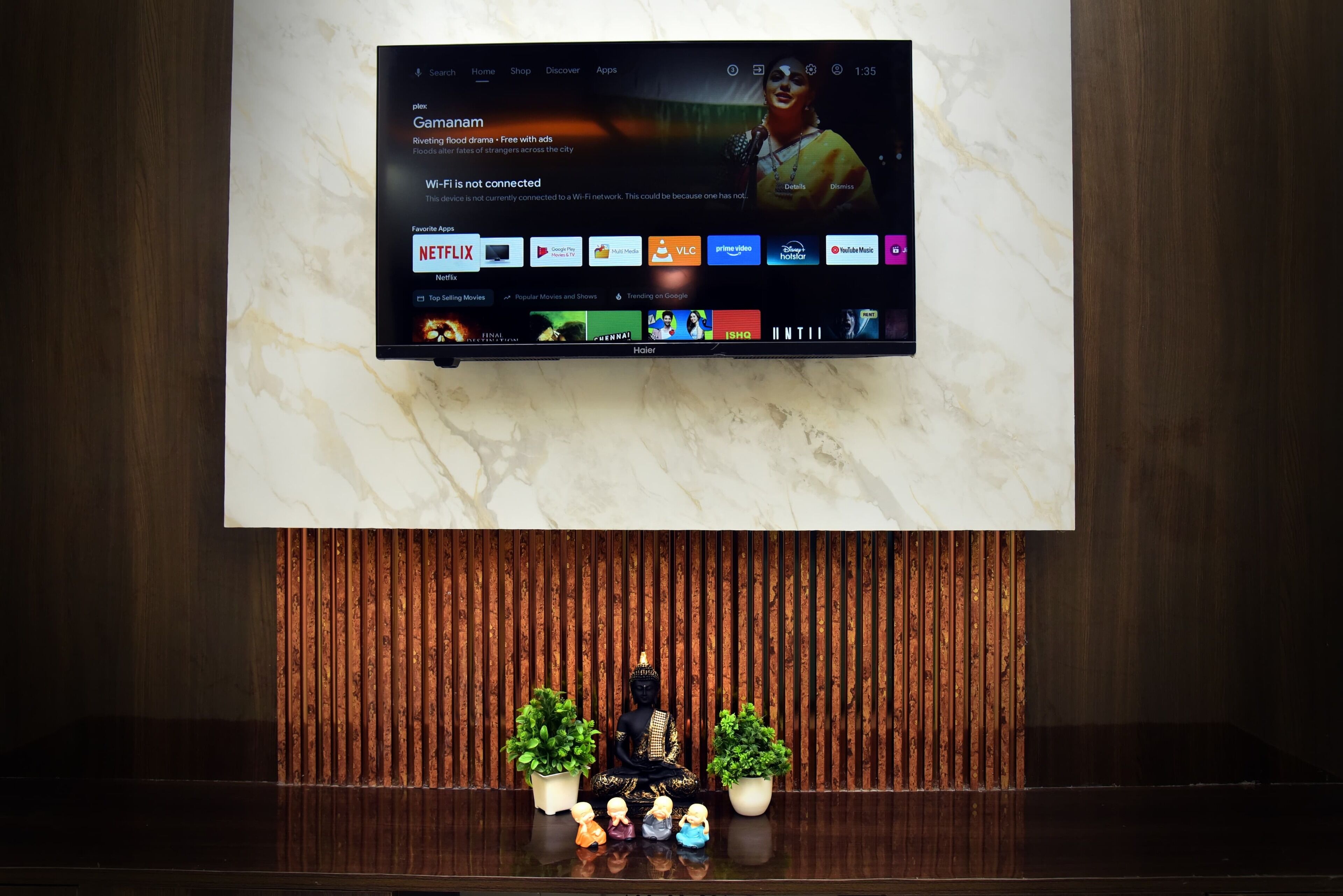 A TV mounted on a marble wall displaying a Netflix interface with a Buddha statue below.