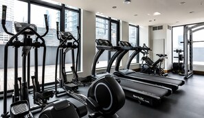 A gym with cardio machines, weightlifting equipment, and large windows offering city views. - Downtown Calgary Haven - Steps to Stampede (Calgary)