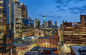 A cityscape with modern high-rise buildings, a prominent tower with a green-lit spire, and a busy street below.
