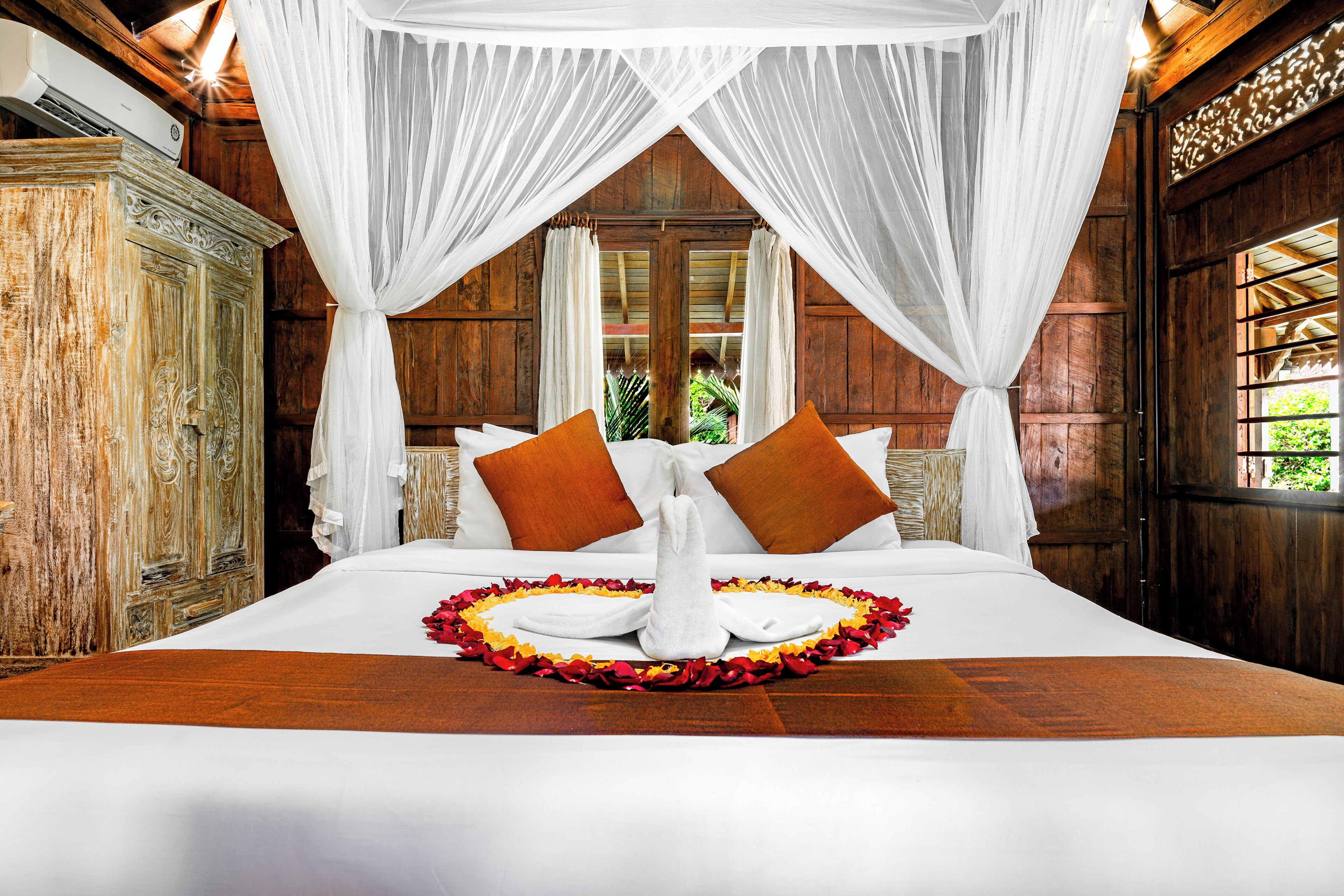 Een groot bed met witte lakens, twee bruine kussens en een decoratief middelpunt.