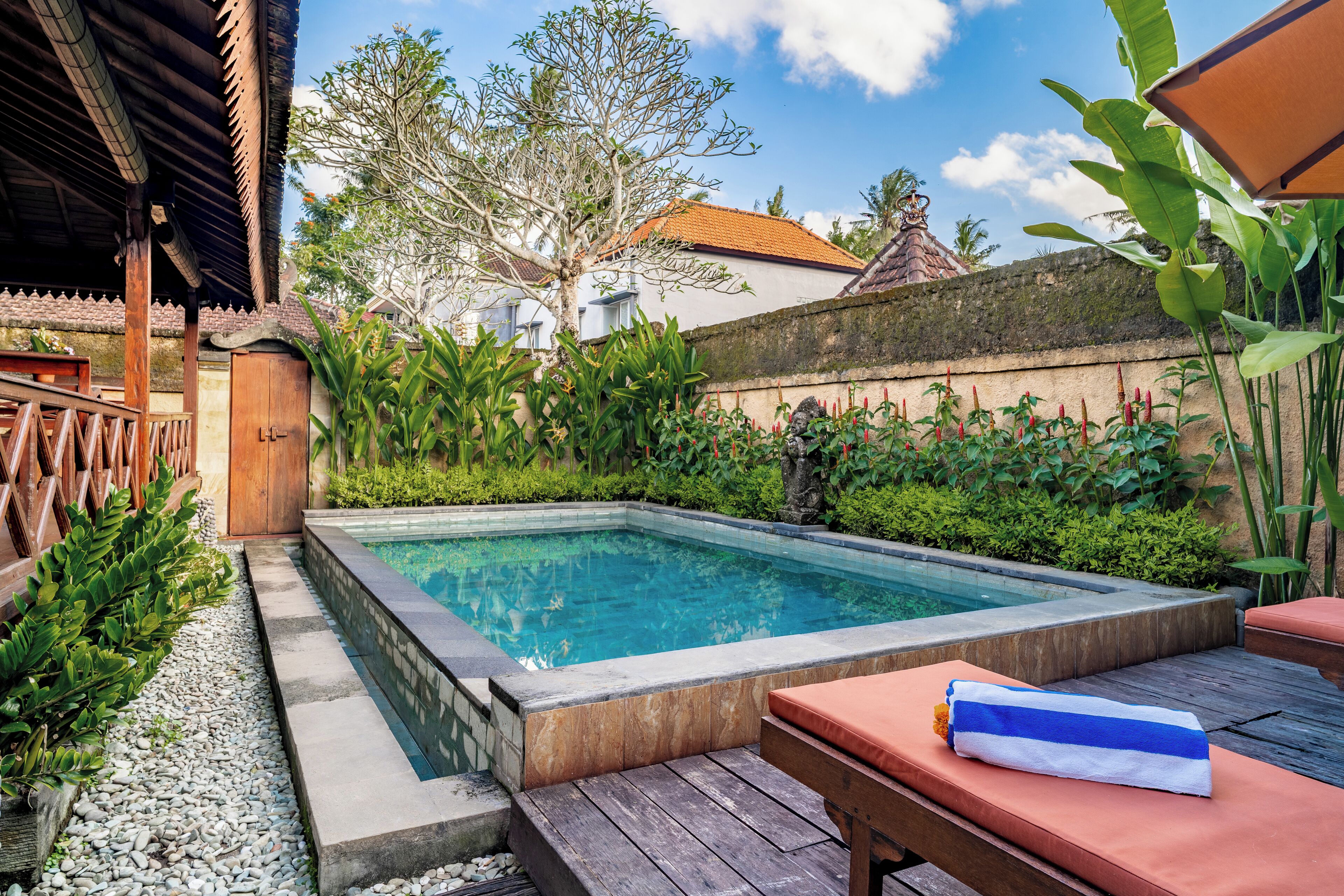 Ein rechteckiger Pool mit Holzterrasse und Liegestühlen.