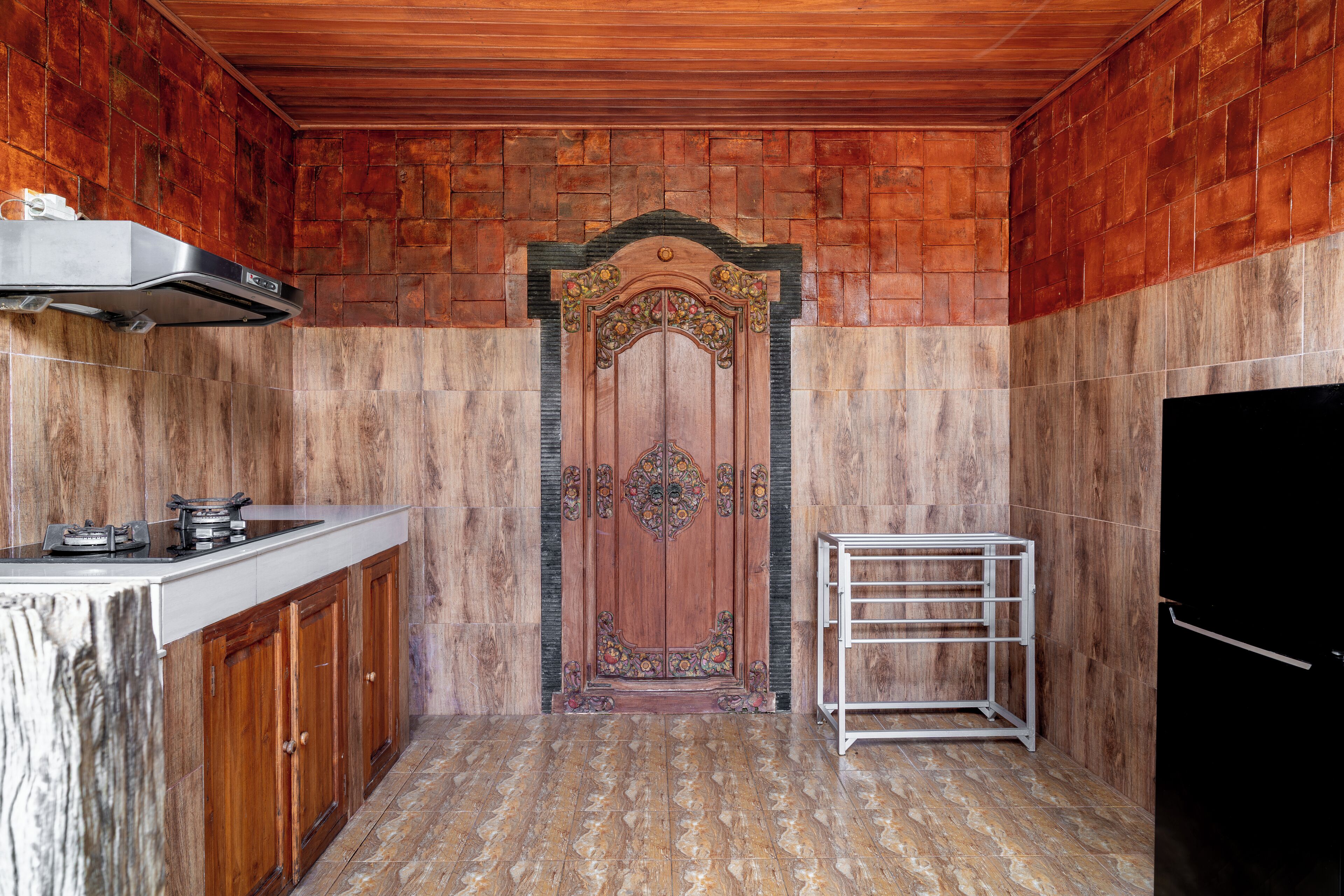 A kitchen with a wooden door, a stainless steel range hood, and a metal rack.