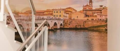A staircase with a view of a bridge over water, leading to a building with a dome.
