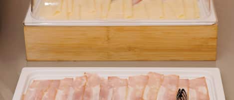 A food display with a glass cover, a wooden box, and a tray of meat slices.