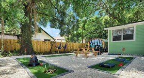 A playground with a swing set, a picnic table, and a small building with graffiti. - Colorful 3BR Retreat w/ Mini Golf + Hammocks | Walk to Ybor (Tampa)