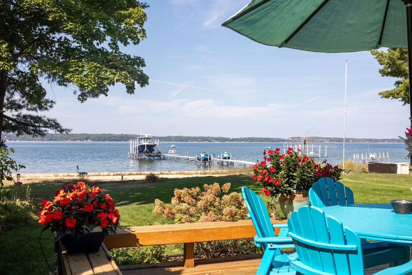 A deck with a view of a lake, a dock with boats, and a gazebo.